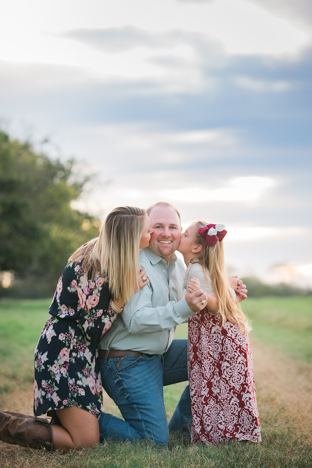 Dad kiss mom and Daughter at sunset at san antonio engagement session