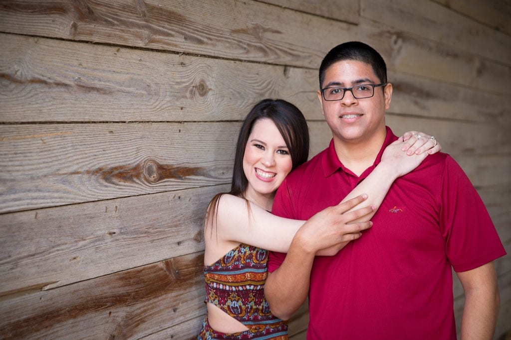 Aamber and Alex engagement session in Gruene Tx her holding him on wooden wall