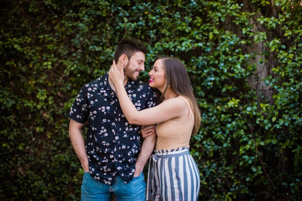 Liz and Ruben engagement standing on greenery wall downtown New Braunfels