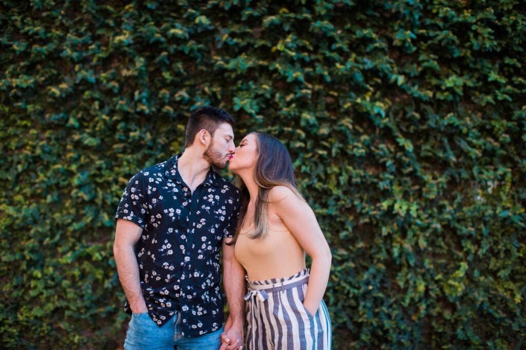 Liz and Ruben engagement kissing on greenery wall downtown New Braunfels