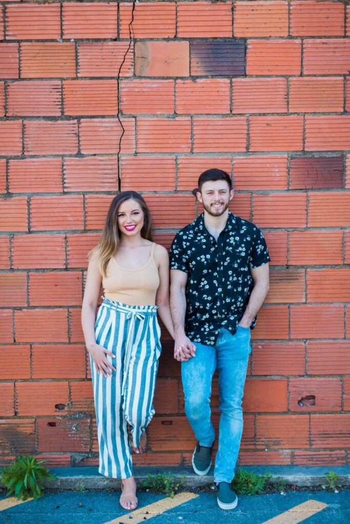 Liz and Ruben engagement standing on red brick wall downtown New Braunfels