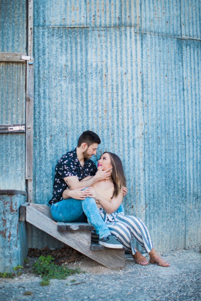 Liz and Ruben engagement looking at each other on tin wall downtown New Braunfels