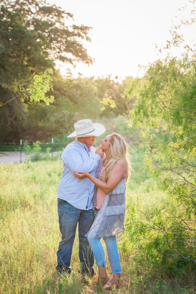 Whitney and Craig's ranch Engagement session back lit holding chin
