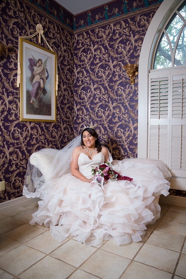 Emilia's Bridal in the ballroom at Castle Avalon bridal suite on the sofa smiling