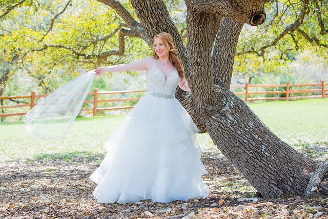 Jamie's Bridal at the Milestone in Boerne in the trees holding veil out