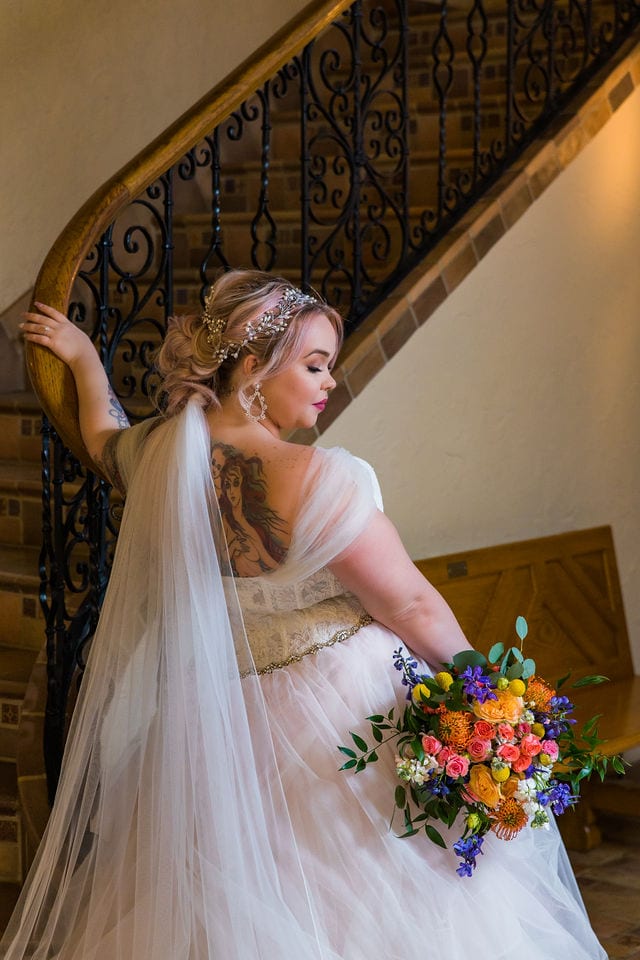 Katie's Bridal session at the McNay posed at the bottom of the stair case back of the dress with flowers