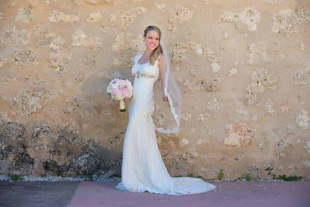 Kimb bridal at Mission Conception portrait on white wall holding veil