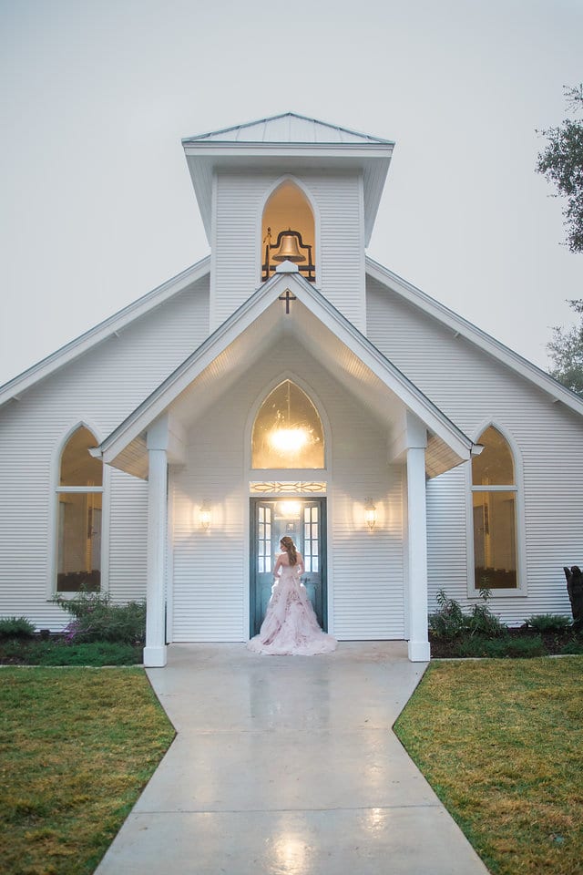 Victoria's bridal at The Chandelier of Gruene bride in the chapel doors outdoors far back