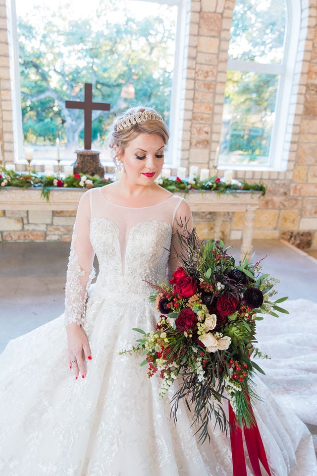 Styled shoot Chandelier of Gruene Christmas Bride looking at her bouquet