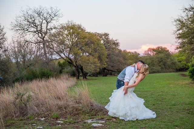 Chelsea and Tyler's Wedding, bride and groom kissing in the field while dipping