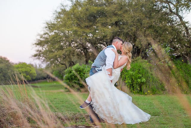 Chelsea and Tyler's Wedding, bride and groom kissing in the field while dipping