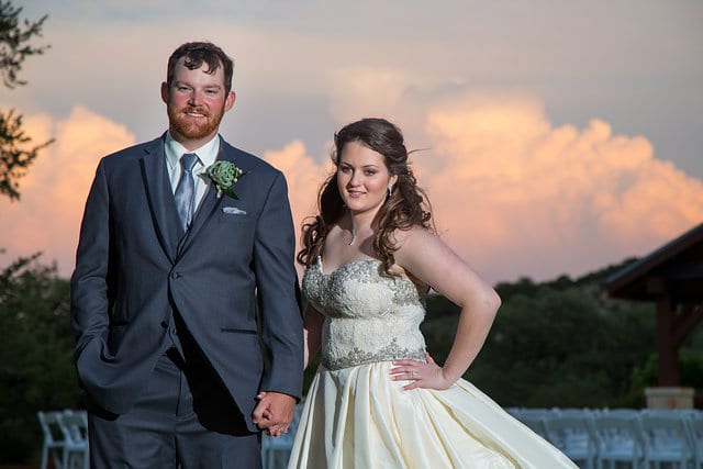 Heather and Wesley's Wedding, bride and groom holding hands with a sunset in back