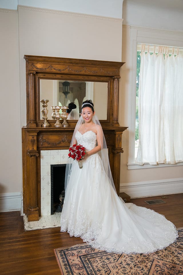 Sarah holding flowers in front of mantel during wedding portraits.