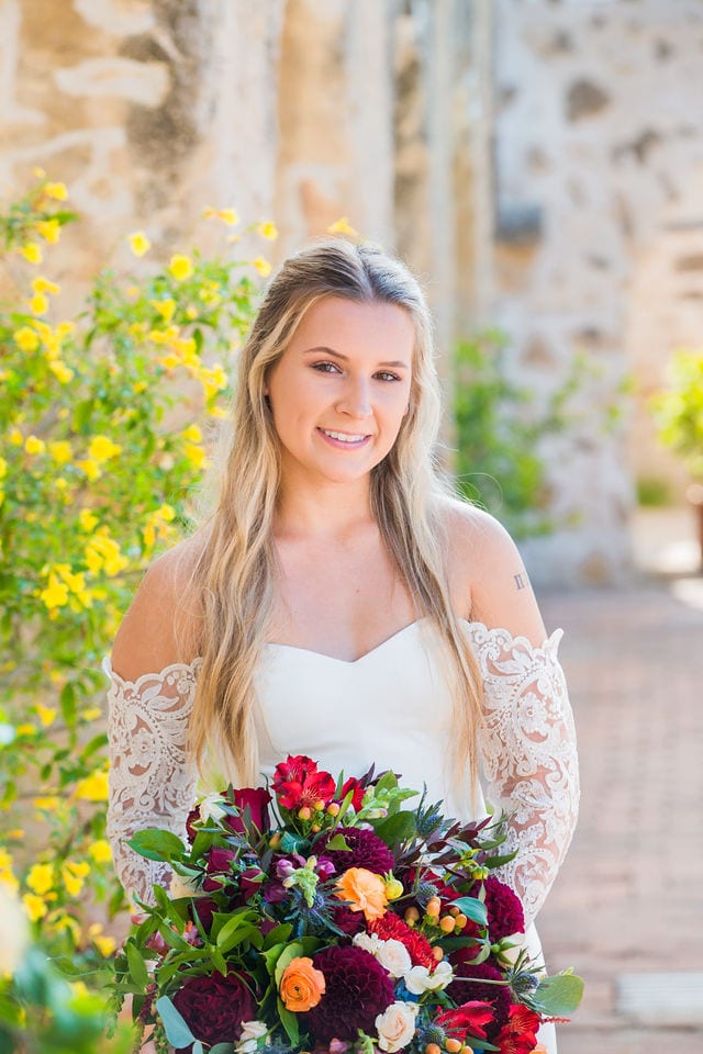 Kelsey's bridal at Mission San Jose outside arches close up with bouquet