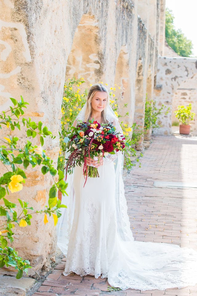 Kelsey's bridal at Mission San Jose outside arches with bouquet