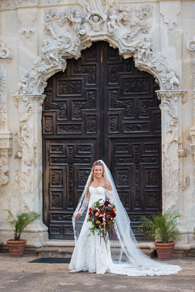Kelsey's bridal at Mission San Jose large doors with a bouquet
