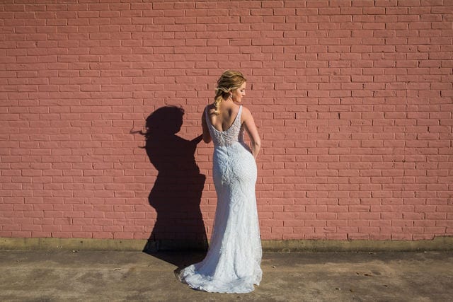 I do the dress I Do with bridal gown on brick wall sunny