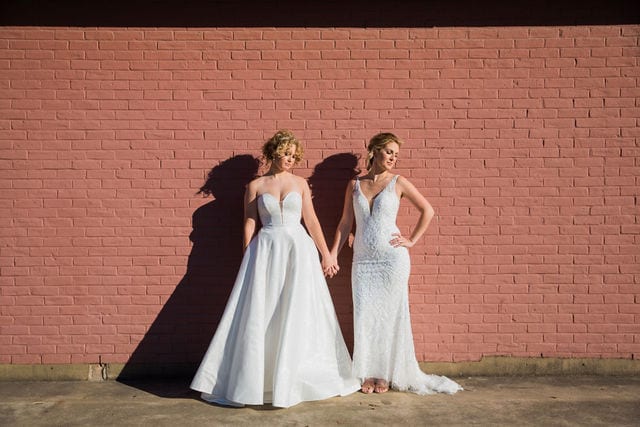 I do the dress I Do with bridal gowns on brick wall sunny