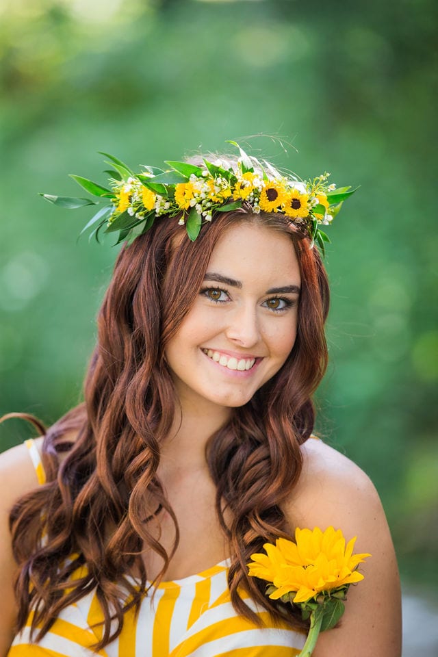 Faith Senior session headshot with flower crown and flower smiling