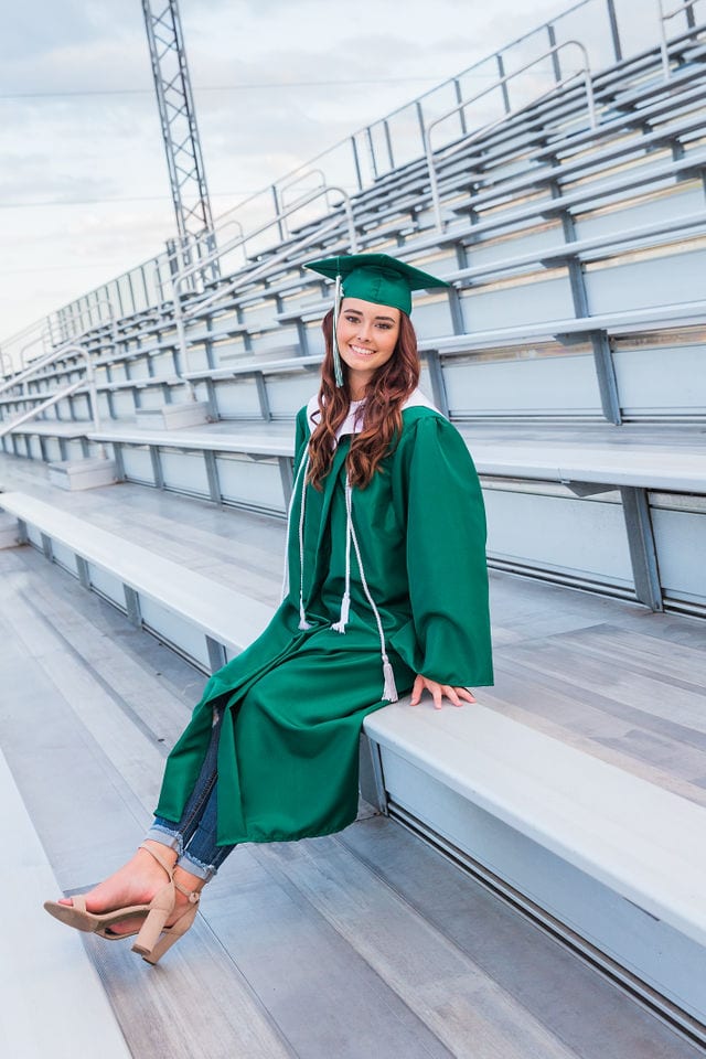 Faith Senior session in Marion cap and gown on bleachers
