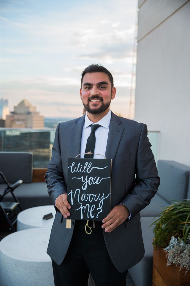 Kunal proposal at the Thompson Hotel, holding the sign on the roof