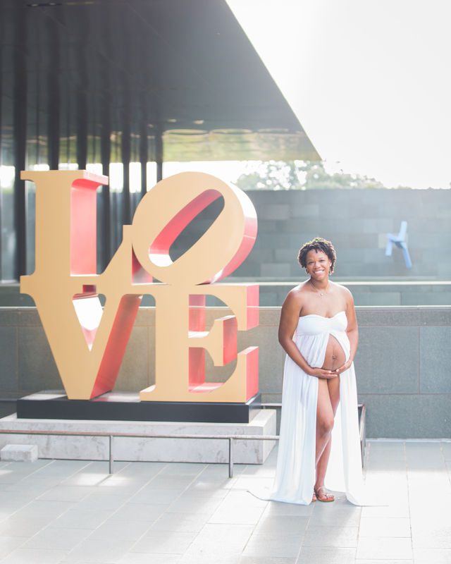 Shara maternity McNay Art Museum holding the belly in white LOVE sign