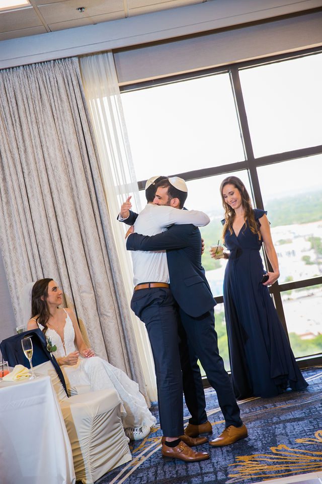 Ophir's San Antonio wedding reception groom and best man hugs