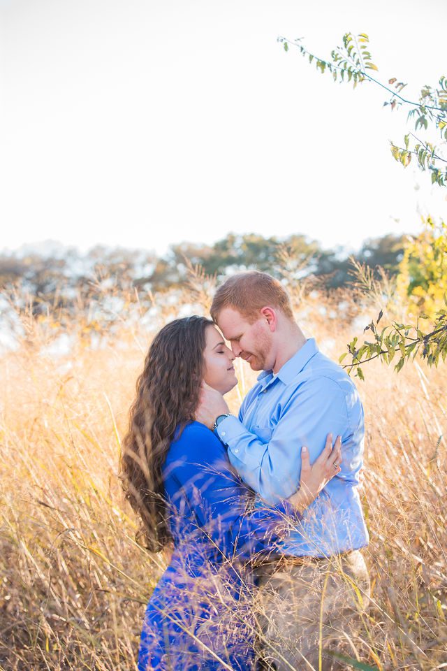 Coltan and Stephanie's engagement in the tall grass at Cibolo Natural Area heads touching