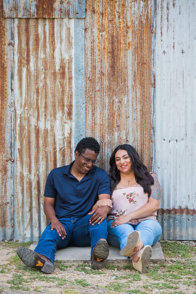 Elexes engagement portrait in Gruene laughing by the tin wall