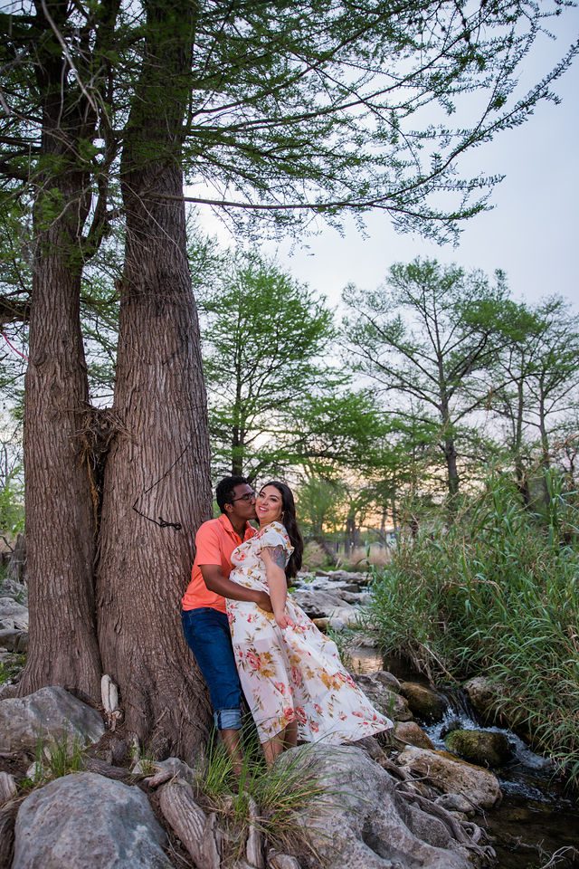 Elexes engagement portrait in Gruene kiss by the river against a tree