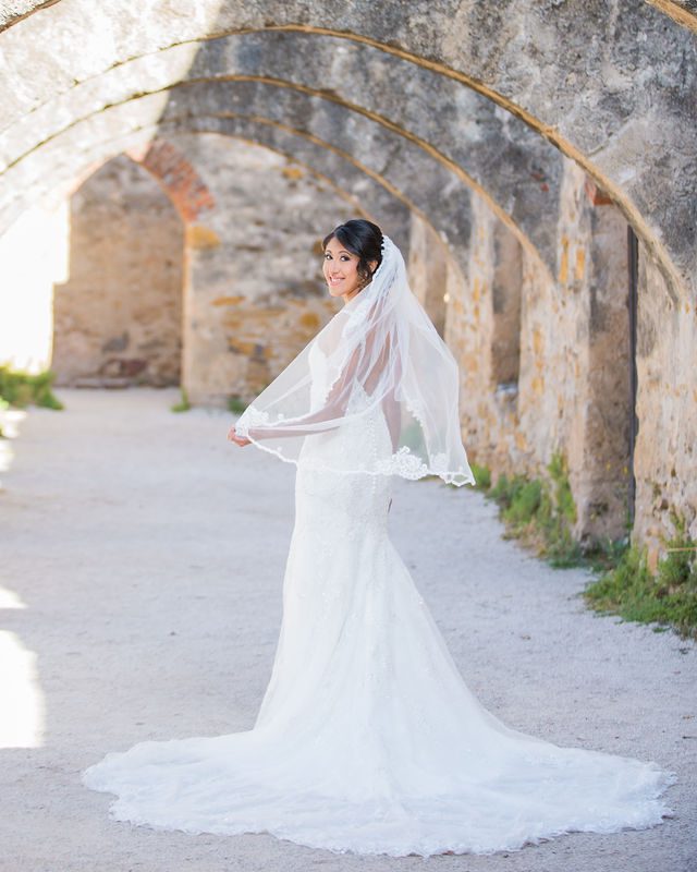 Kylee's bridal at Mission San Jose in the arches holding the veil looking back