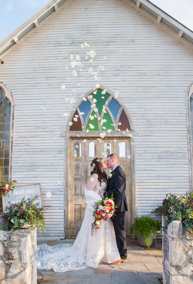 Simon wedding at Gruene Estate in New Braunfels couple portrait in front of the chapel petals falling