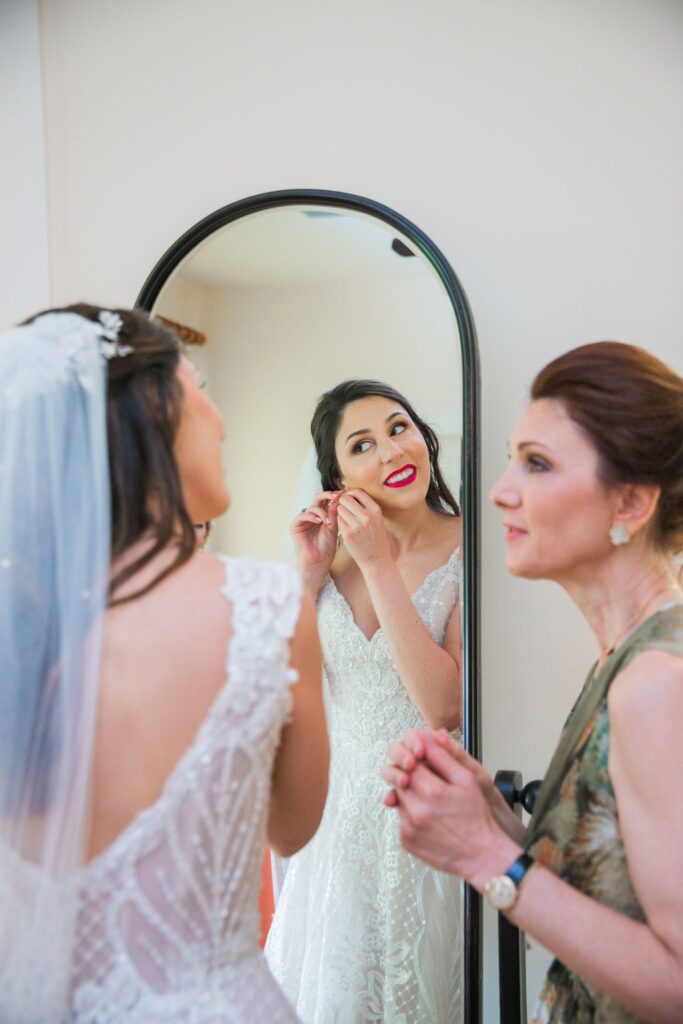 The Hamet wedding in San Antonio. The bride in the mirror putting on bridal jewelry