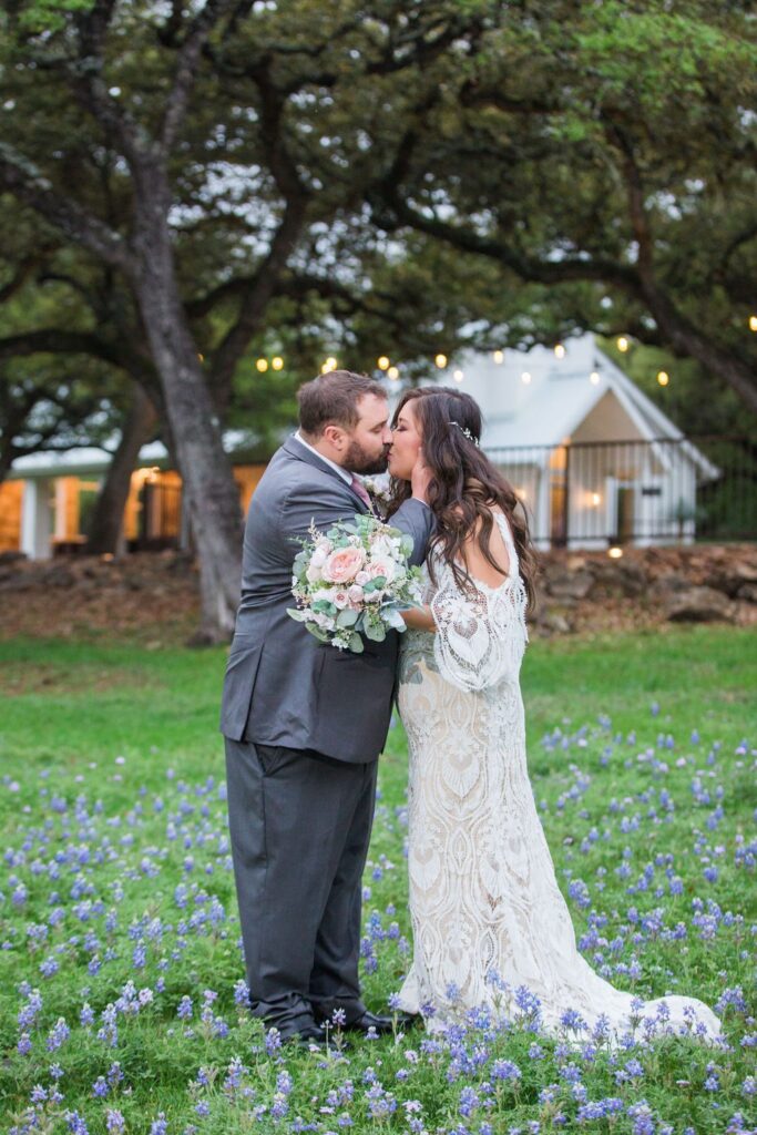 Missie's wedding at the Chandelier of Gruene couple kiss in the bluebonnets