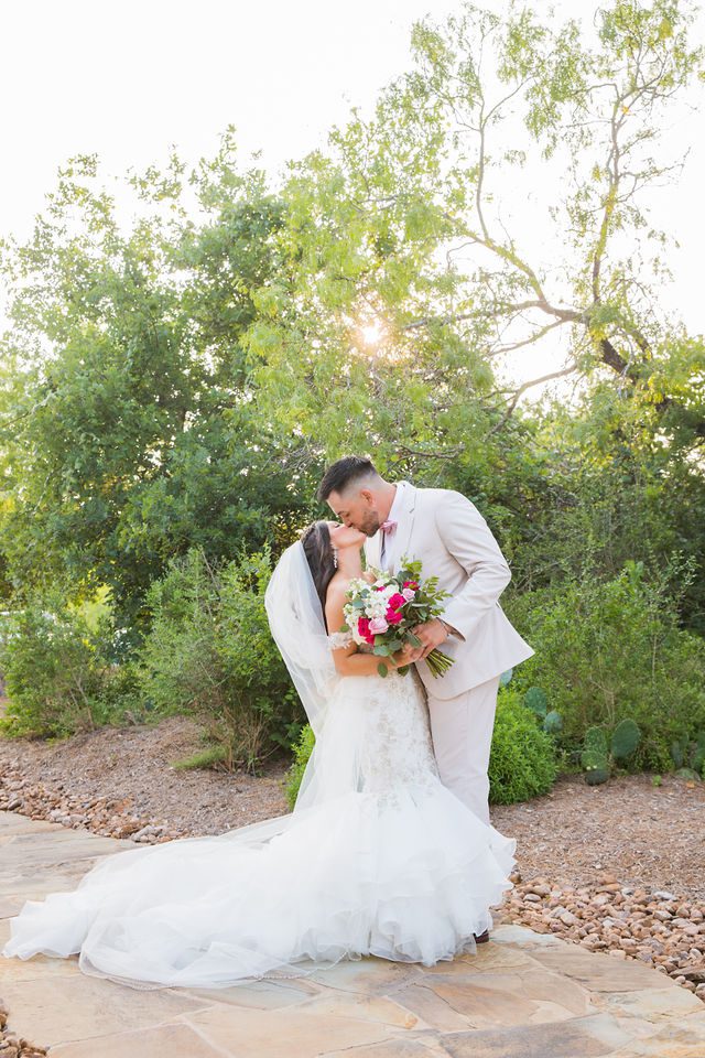 Hollubs wedding at Geronimo Oaks in San Antonio groom kissing bride in the sun