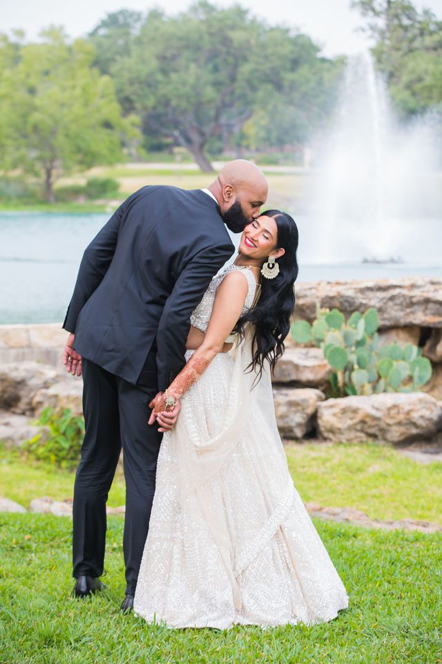 Nida wedding Club of Garden Ridge in San Antonio kiss on the cheek by the fountain