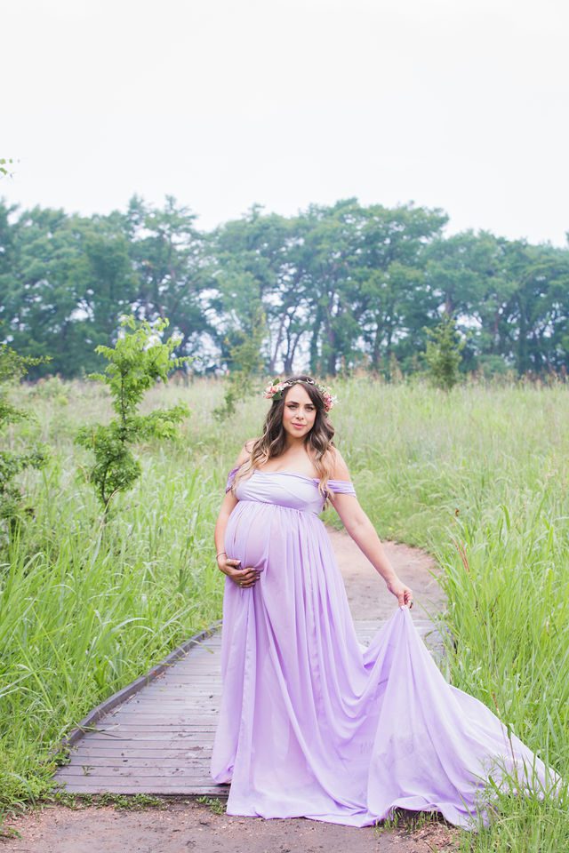 Yoli maternity session at Cibolo Natural Area in the grass holding the dress