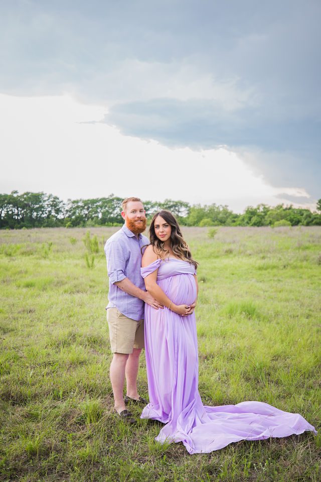 Yoli maternity session at Cibolo Natural Area couple in the grass purple dress
