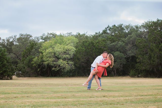 Brighten's engagement session at Western Sky in San Antonio in the field kissing