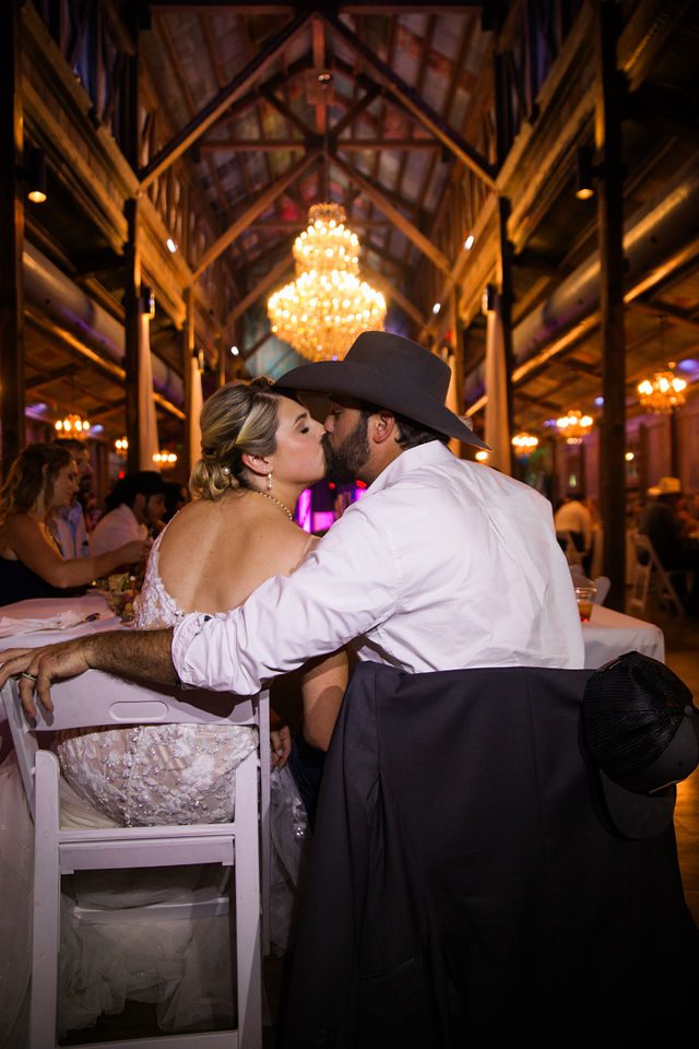 Kirt A's wedding at Eagle Dancer Ranch bride and groom kiss at table