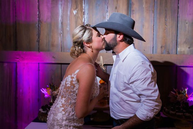 Kirt A's wedding reception at Eagle Dancer Ranch cake cutting kiss
